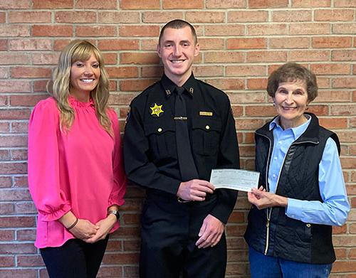 Verna Feather, Recruit Aaron Pacos, and 雷切尔Waid stand together, holding scholarship check